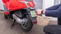 Moped Roller Kennzeichen wird angeschraubt