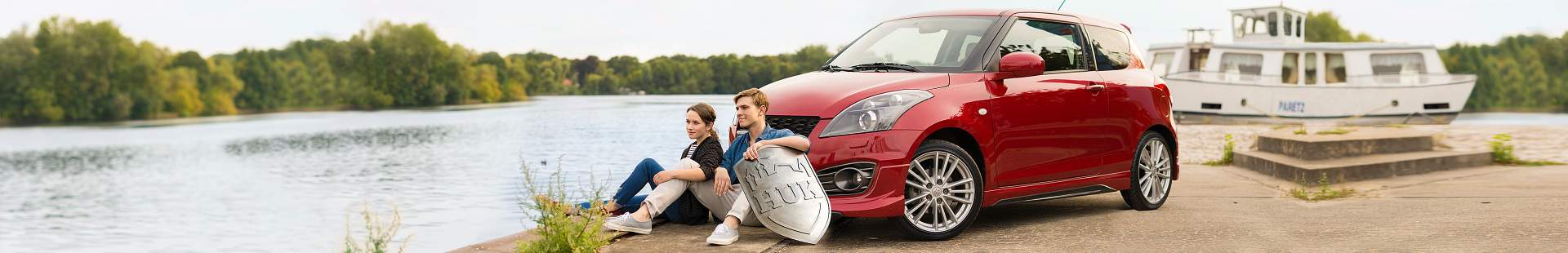 Mann und Frau sitzen vor einem Auto am See