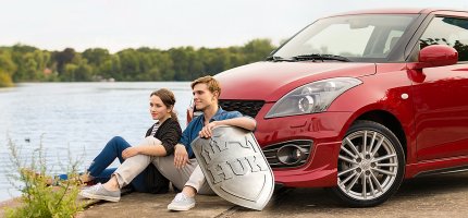 Mann und Frau sitzen vor einem Auto am See