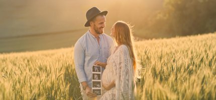 Schwangere Frau hält Ultraschallbilder in der Hand mit ihrem Mann