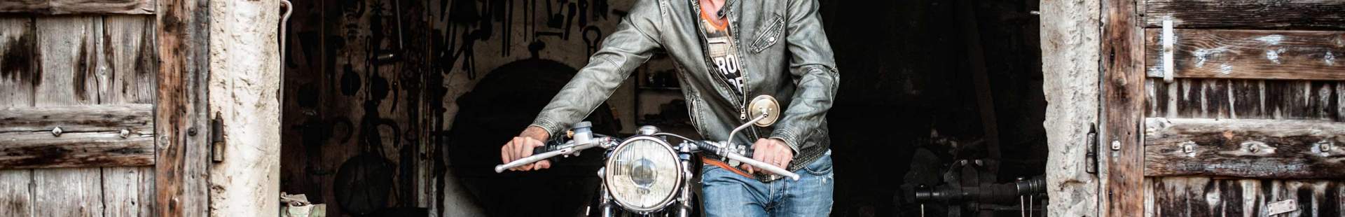 Mann schiebt Motorrad aus Garage
