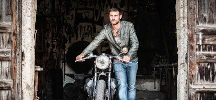 Mann schiebt Motorrad aus Garage