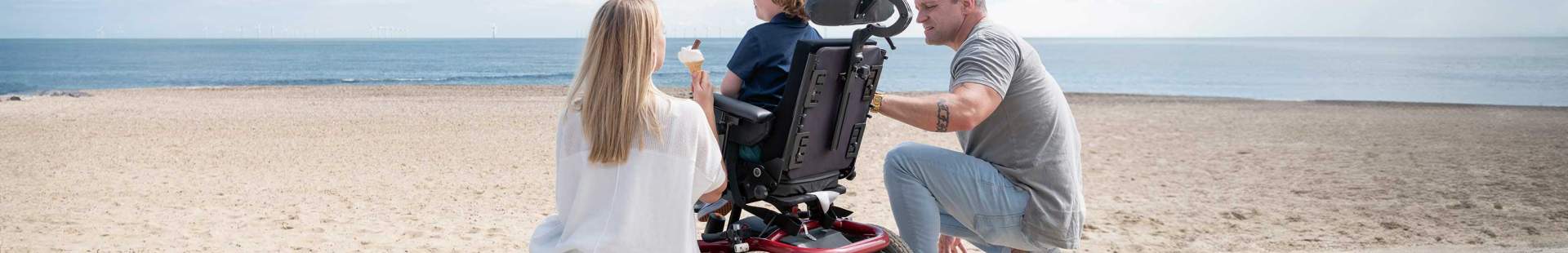 Eine Familie am Strand, das Kind sitzt im Rollstuhl.