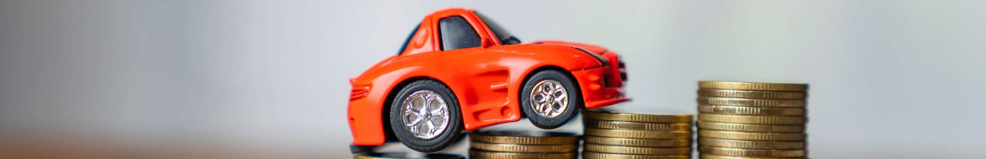 Kleines rotes Spielzeugauto auf einem Münzstapel