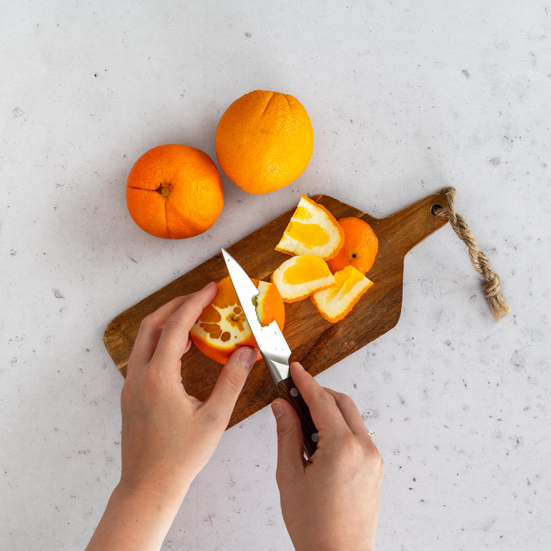 Schritt 1: Orangen werden auf Brettchen mit einem Messer geschält