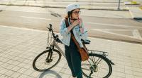 Frau mit Fahrrad setzt ihren Helm auf