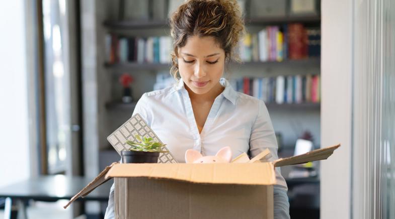 Frau verlässt das Büro mit gepackten Sachen