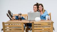 Mutter und Tochter sitzen mit Kaffee gemütlich am Laptop