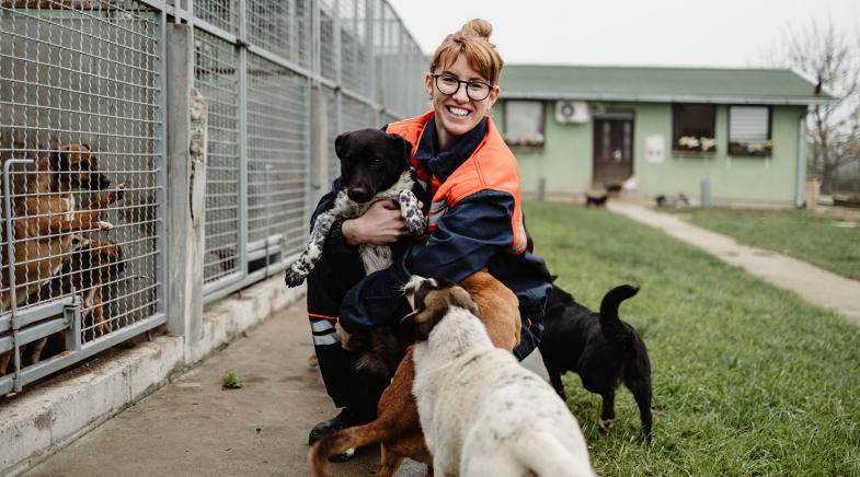 Frau sitzt mit Hunden vor Tierheim