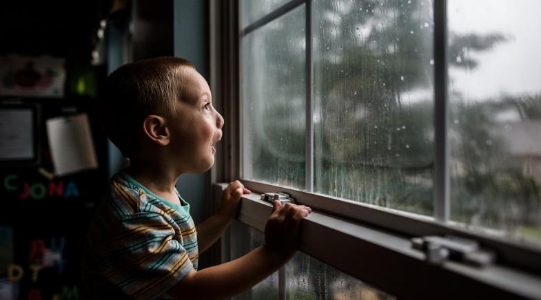 Kleiner Junge steht am Fenster