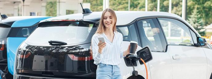 Frau vor einem ladenden Elektroauto