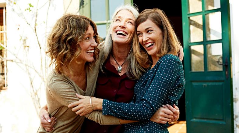 Drei Frauen halten sich lachend im Arm