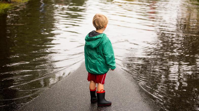 Junge steht vor Hochwasser