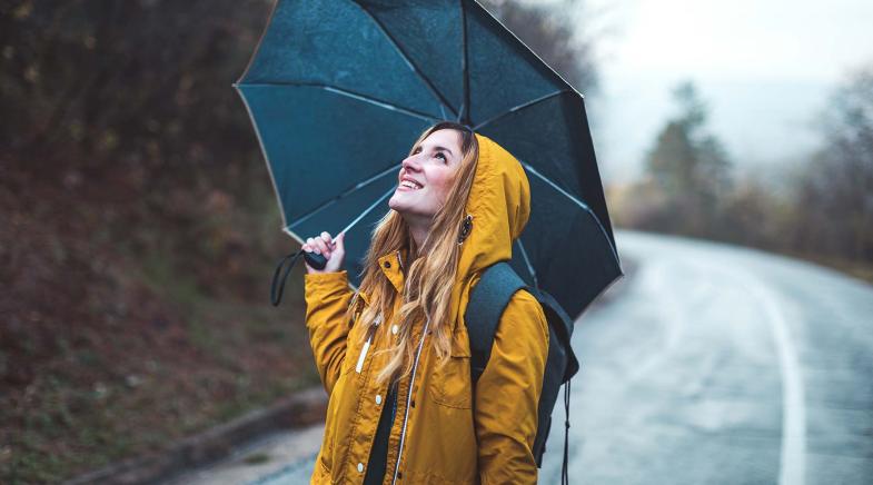 Frau steht mit Regenschirm auf der Straße