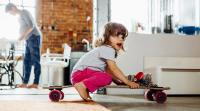 Kleines Mädchen mit Skateboard in einer Wohnung
