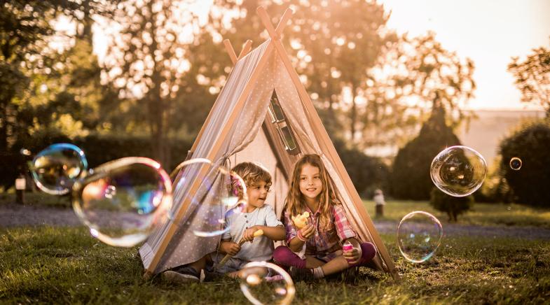 Kinder machen Seifenblasen im Garten in einem Zelt