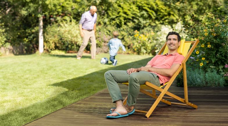 Ein Mann sitzt zufrieden in seinem Garten