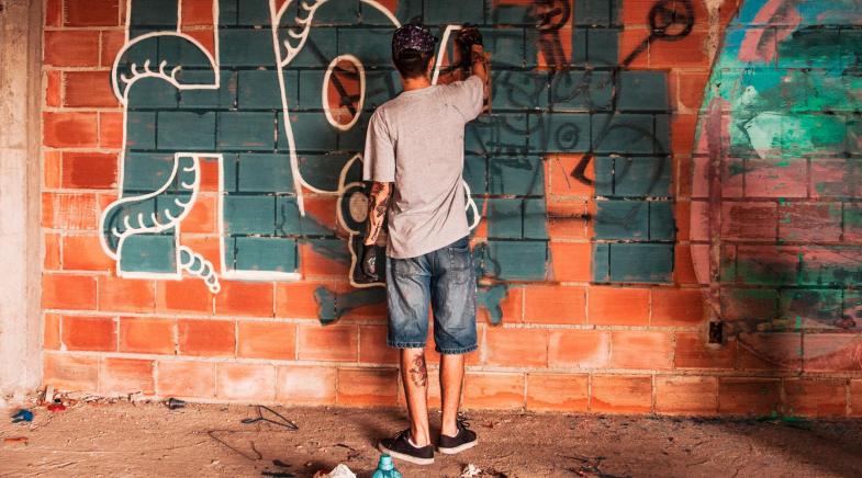 Junge sprüht ein Grafitti an die Wand
