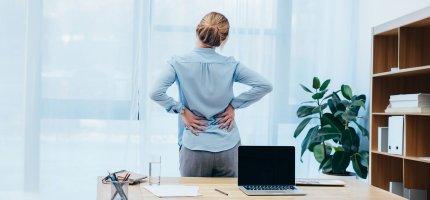 Frau mit Rücknschmerzen hält sich den Rücken