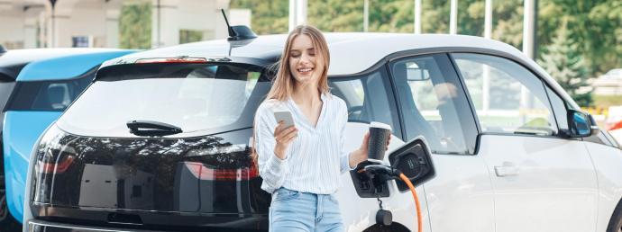 Frau vor einem ladenden Elektroauto