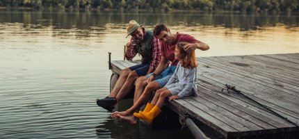 Familie sitzt auf einem Steg  am See