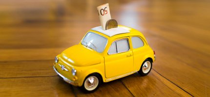Kleines gelbes Spielzeugauto mit Geldschein