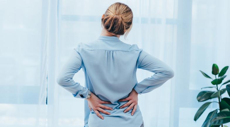 Frau mit Rückenschmerzen hält sich den Rücken