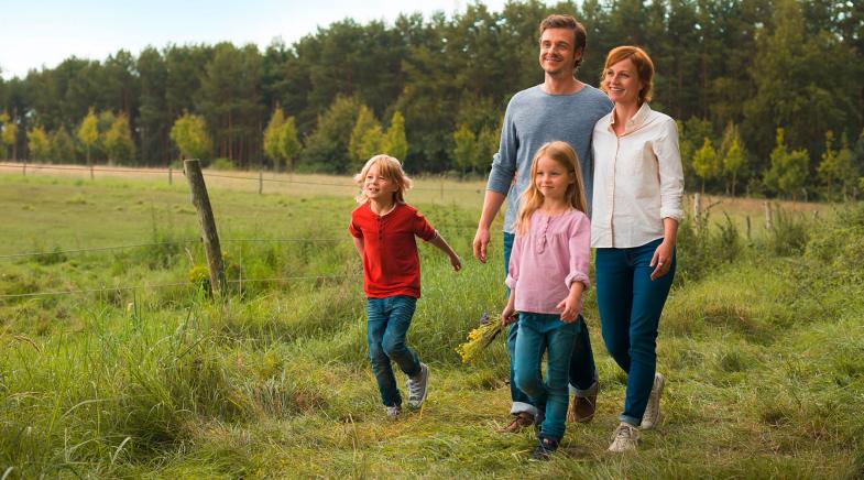 Eine Familie mit zwei Kindern läuft auf einer grünen Wiese